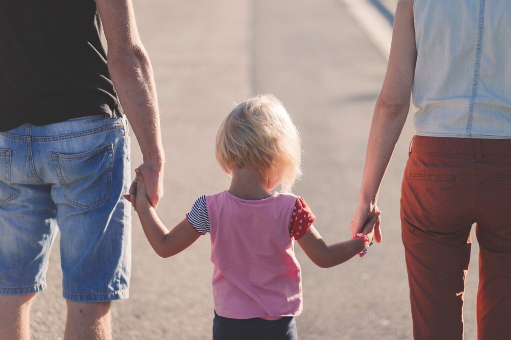 A child holding hands of parents.