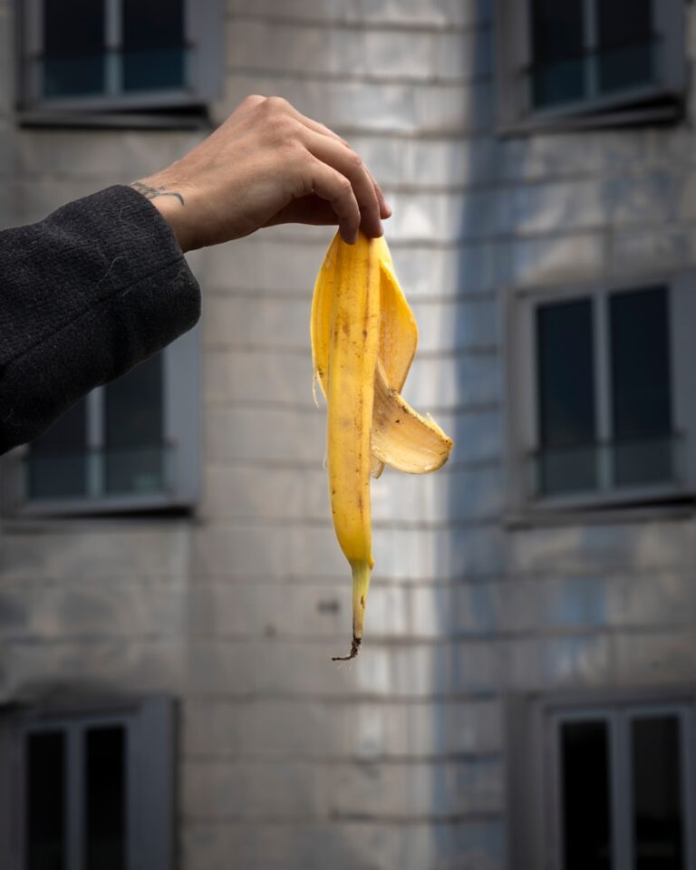 A hand holds up a banana peel.